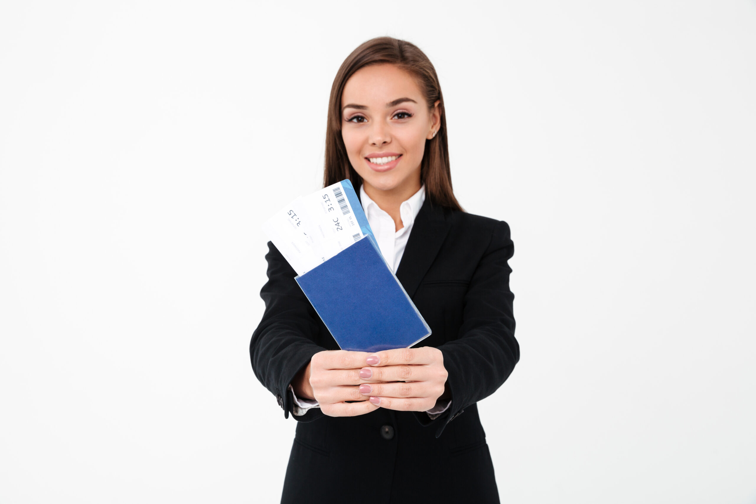 Image of happy pretty businesswoman standing isolated over white background showing tickets and passport. Looking camera. Focus on passport.